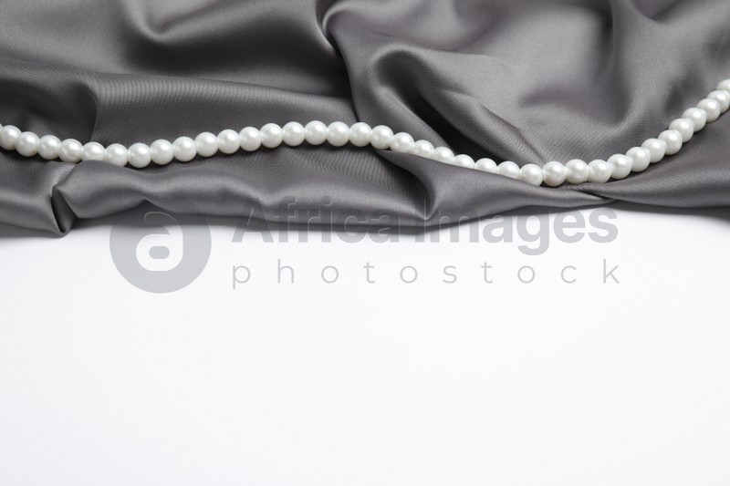 Beautiful pearls and grey silk on white background