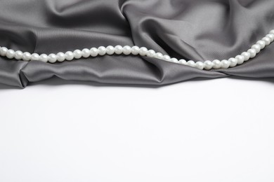 Beautiful pearls and grey silk on white background