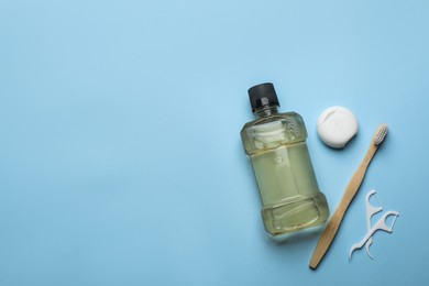 Mouthwash, toothbrush and dental floss on light blue background, flat lay. Space for text