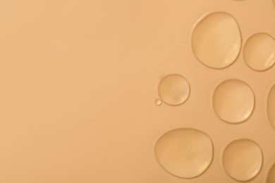 Drops of hydrophilic oil on beige background, flat lay. Space for text