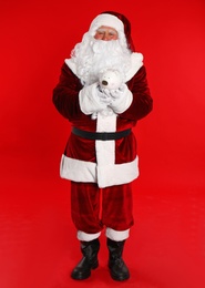 Santa Claus holding piggy bank on red background