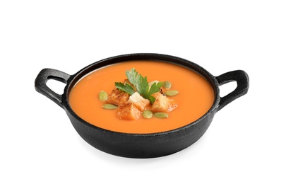 Tasty creamy pumpkin soup with croutons, seeds and parsley in bowl on white background