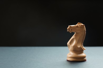Wooden knight on table against dark background, space for text. Chess piece