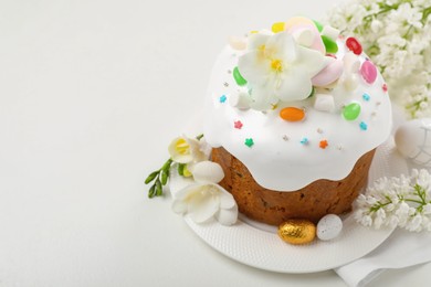 Photo of Traditional Easter cake with painted eggs and flowers on white table, space for text