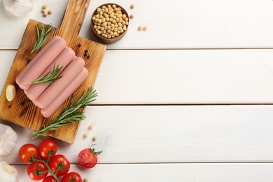 Fresh raw vegetarian sausages and vegetables on white wooden table, flat lay. Space for text
