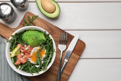 Photo of Delicious salad with boiled egg, salmon and avocado served on white wooden table, flat lay. Space for text