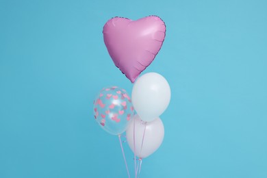 Photo of Bunch of heart and round shaped balloons for birthday party on light blue background