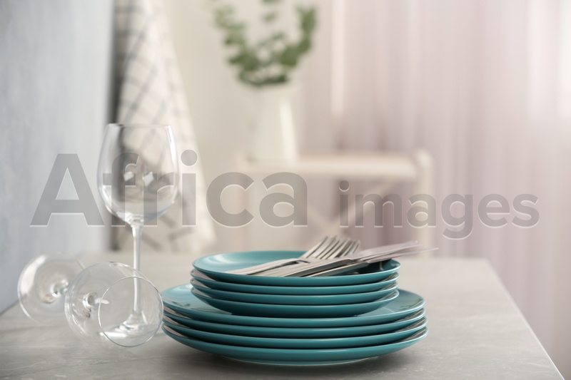 Photo of Set of clean dishware, cutlery and wineglasses on grey table indoors. Space for text