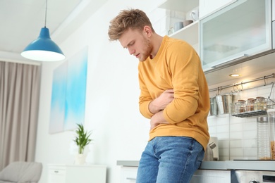 Young man having nausea in kitchen. Space for text