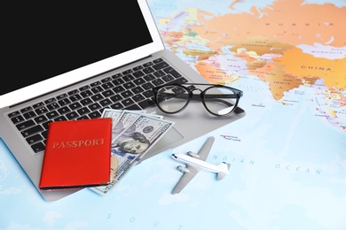 Composition with laptop, toy plane, money and passport on map. Travel agency