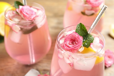 Photo of Delicious refreshing drink with rose flowers and lemon slices on table, closeup