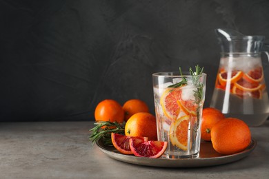 Delicious refreshing drink with sicilian orange and rosemary near fresh ingredients on grey table. Space for text