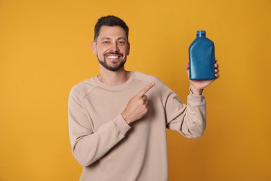 Man pointing at blue container of motor oil on orange background