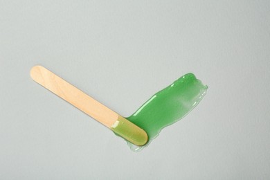 Spatula with wax on grey background, top view