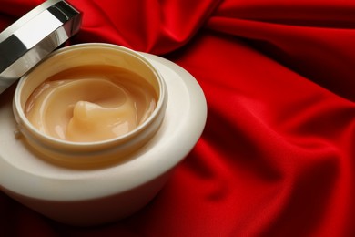 Photo of Open jar of hair care cosmetic product on red fabric, closeup. Space for text