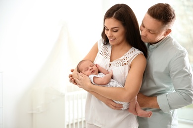 Happy couple with their newborn baby at home. Space for text