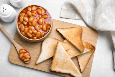 Toasts and delicious canned beans on white table, flat lay