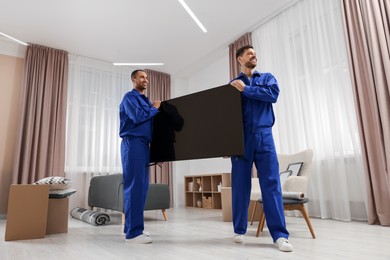Photo of Male movers carrying plasma TV in new house