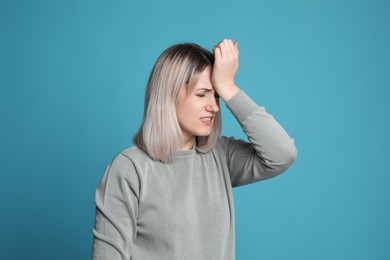 Woman suffering from headache on light blue background