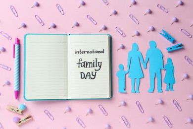 Happy International Family Day. Flat lay composition with notebook and paper people cutout on pink background