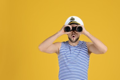 Sailor looking through binoculars on yellow background, space for text