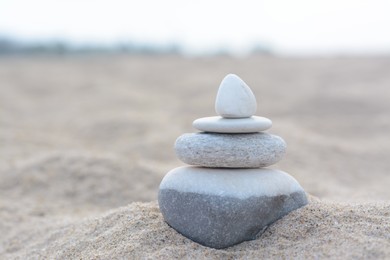 Photo of Stack of stones on sandy beach near sea, space for text