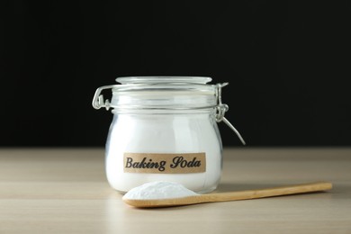 Jar and spoon with baking soda on wooden table
