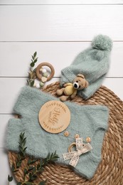 Children's clothes, toys and green plant on white wooden table, top view