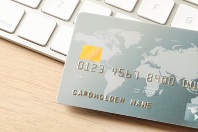 Photo of Online payment concept. Bank card and computer keyboard on wooden table, closeup