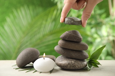Woman stacking stones on table against blurred background, closeup. Zen concept
