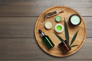 Different hemp cosmetics, green leaf and seeds on wooden table, top view. Space for text