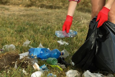 Woman in gloves with trash bag collecting garbage in nature, closeup