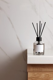 Aromatic reed air freshener on white table indoors, space for text