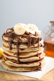 Tasty pancakes with sliced banana served on wooden board, closeup