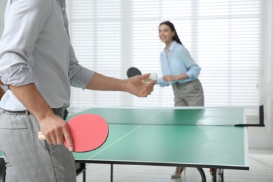 Business people playing ping pong in office, focus on tennis racket