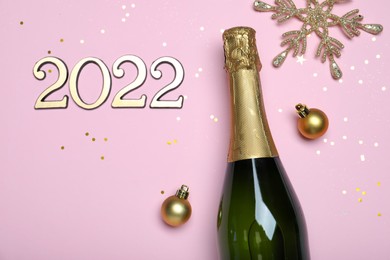 Happy New Year 2022! Flat lay composition with bottle of sparkling wine on pink background, space for text