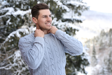Happy man wearing warm sweater snowy fir tree