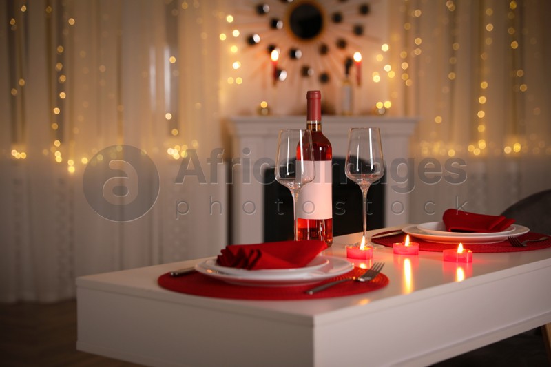 Romantic table setting with wine and candles for Valentine's day dinner indoors