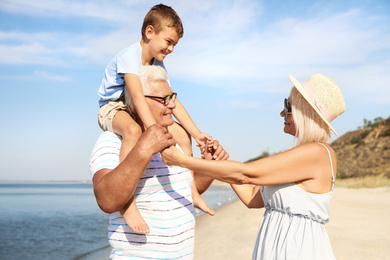 Cute little boy with grandparents spending time together on sea beach