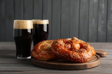 Tasty pretzels and glasses of beer on wooden table, space for text