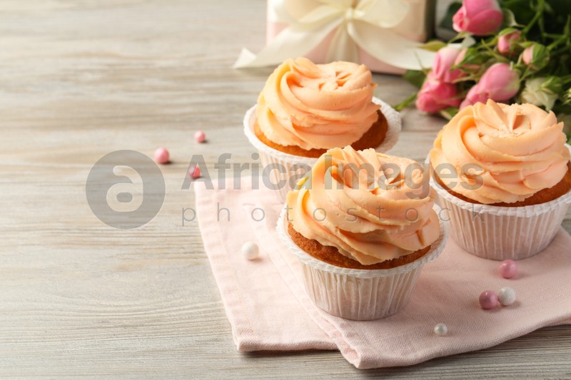 Photo of Tasty cupcakes with cream on wooden table, space for text