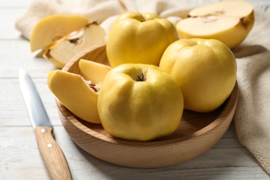 Fresh ripe organic quinces and knife on white wooden table