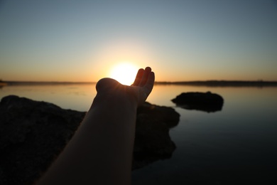 Woman reaching for sun outdoors, closeup. Healing concept