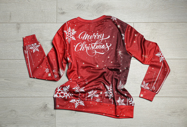 Photo of Warm Christmas sweater on wooden table, top view
