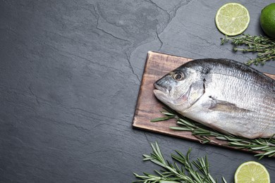 Flat lay composition with fresh raw dorado fish and ingredients on black table, space for text