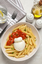 Delicious pasta with burrata cheese and sauce served on light grey table, flat lay
