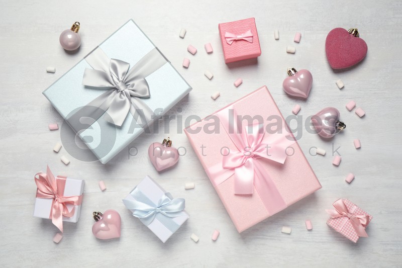 Beautiful gift boxes and festive decor on white table, flat lay