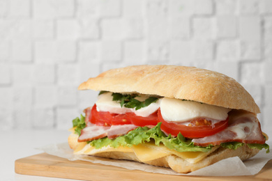Photo of Delicious sandwich with fresh vegetables and mozzarella on white table