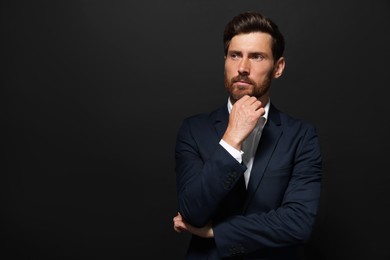 Portrait of handsome bearded man looking away on black background. Space for text