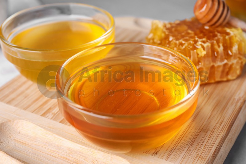Photo of Tasty organic honey on table with board, closeup